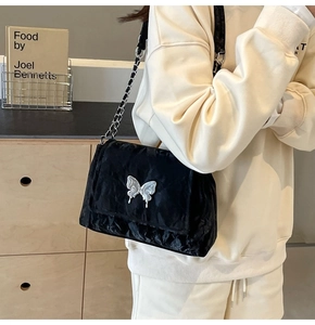 Détail du sac cabas plissé noir avec breloque papillon argentée et bandoulière chaîne