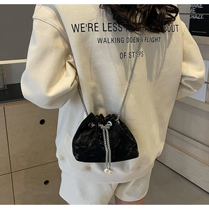 Detail view of black velvet bucket bag with drawstring closure and pearl accents