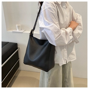 Close-up of black PU leather bucket bag with adjustable strap on a female model