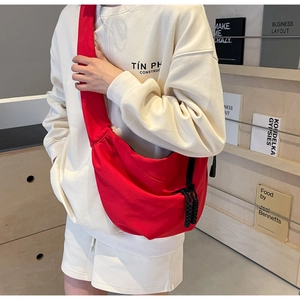 Detailed view of the bright red crescent crossbody bag featuring black woven zipper pulls