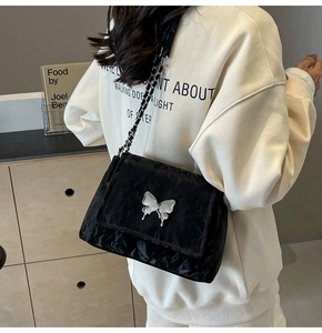 Détail du sac cabas en PU noir avec un grand papillon en métal argenté et une chaîne