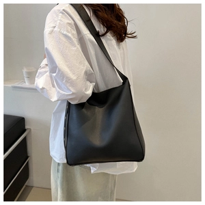 Detailed side view of black minimalist leather tote bag with rivet studs and wide strap
