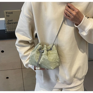 Detail of mint green velvet bucket bag featuring pearl drawstring and silver chain strap