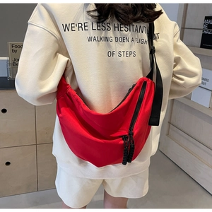 Detail view of red crescent nylon bag with adjustable black strap and woven zipper pullers