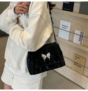 Détail du sac sous l'aisselle en velours noir avec papillon argenté et chaîne