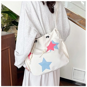 Dettaglio della borsa tote bianca con toppe a stella colorate e accenti di coulisse