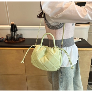 Detail of light green quilted PU leather handbag with drawstring decor and round handle