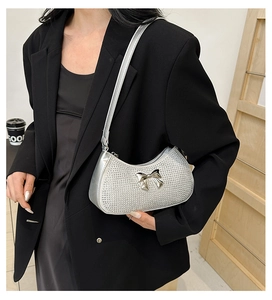 Detail of silver rhinestone crescent bag with metal bow buckle shown on a model
