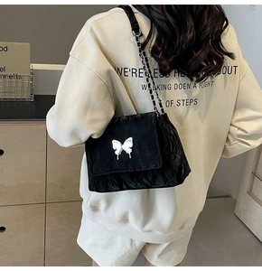 Détail de l'accessoire papillon argenté sur un sac fourre-tout en cuir noir texturé