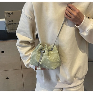 Detail of light green bucket bag with pleated velvet texture and white pearl charms