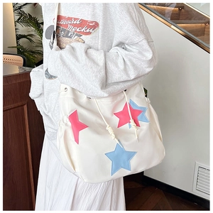Dettaglio borsa a tracolla in nylon bianco con applicazioni a stella rosa e blu e coulisse