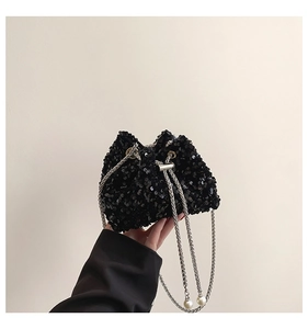 Detailed close-up of a black sequin bucket bag featuring a silver chain and pearl accents