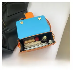 Interior view showing orange and blue contrast bag capacity with magnetic gold buckles
