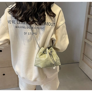 Detail of light green pleated bucket bag with silver chain strap and pearl drawstring