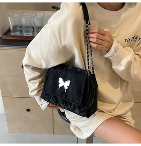 Détail du sac bandoulière en PU plissé noir avec grand ornement papillon en métal argenté