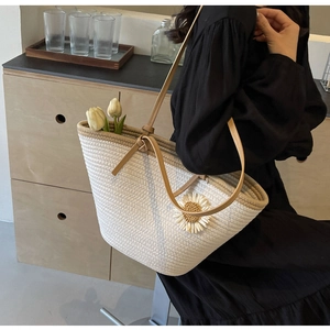 Detail of a large woven tote bag with 3D daisy appliqués and brown leather straps