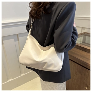 Hobo style cream white shoulder bag shown with a modern grey suit for a chic office look