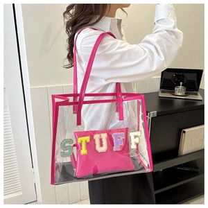 Detail of pink PVC tote bag with colorful STUFF towel embroidery worn by model