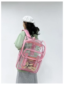 Rear view of a model wearing a pink transparent PVC backpack with a cute teddy bear inside