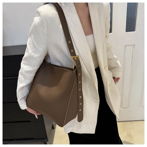 Detail view of deep brown matte leather bucket bag with wide grommet shoulder strap