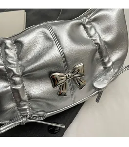Detail of silver crossbody bag featuring metallic bow and drawstring texture