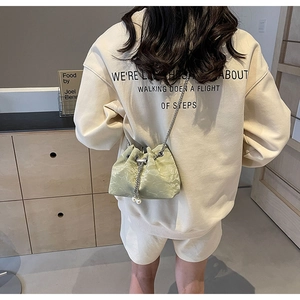 Detail of light green drawstring bucket bag with silver chain and white pearl charms