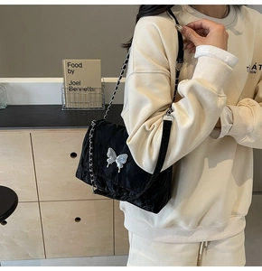 Détail du sac cabas matelassé noir avec boucle papillon argentée et bandoulière chaîne