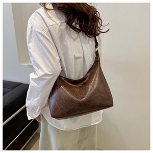 Side view of trendy brown PU leather hobo bag worn by model for spring fashion style