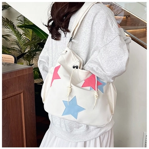 Dettaglio di una grande borsa tote color crema con motivi a stelle e chiusura a coulisse