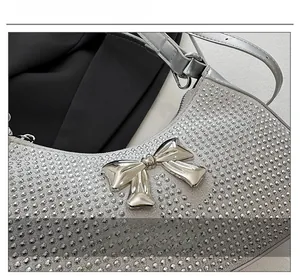Close-up of silver rhinestone handbag with metallic bow and faux crocodile strap