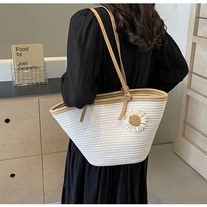 Detailed woven texture of off-white tote bag featuring a daisy charm and brown leather strap