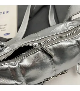 Macro detail of the silver metallic quilted bag showing a high-gloss smooth metal zipper