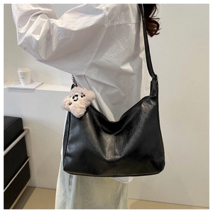 Detail of black PU leather shoulder bag with a cute light pink plush bear pendant