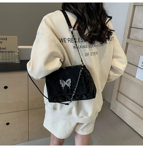 Détail du sac cabas plissé noir avec emblème papillon argenté et bandoulière chaîne