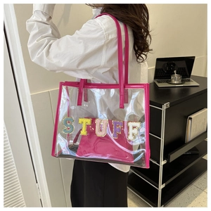 Detailed view of pink PVC transparent tote bag with STUFF sequin embroidery on model