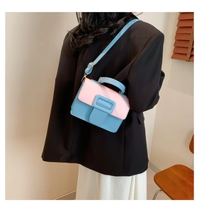 Detail showing pink and blue contrast crossbody bag worn by a model in casual blazer