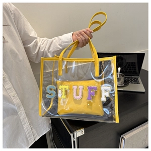 Close-up of yellow transparent PVC tote bag with 'STUFF' embroidered inner pouch
