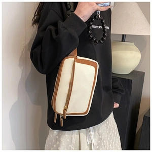 Close-up of stylish cream PU leather crossbody bag with brown edges and gold zippers