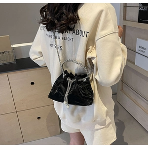 Detail of black velvet drawstring bucket bag with pearl tassels and silver metal chain