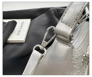 Detailed macro view of high-quality silver metallic hook and rhinestone decor on a PU handbag