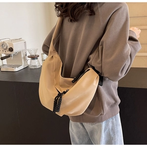 Khaki crescent crossbody bag shown on a model in a cozy cafe, minimalist urban style