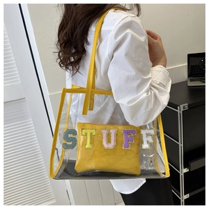 Detail of yellow PVC tote bag featuring colorful glitter STUFF embroidery and inner pouch