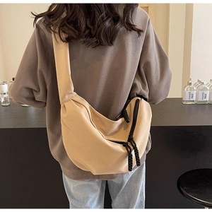 Detailed back view of a beige crossbody bag with wide shoulder strap and woven zipper pull