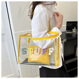 Detail of transparent PVC tote bag with yellow trim and colorful STUFF lettering patch