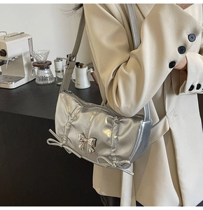 Detailed view of trendy silver PU crossbody bag with elegant bow accents and pleated texture