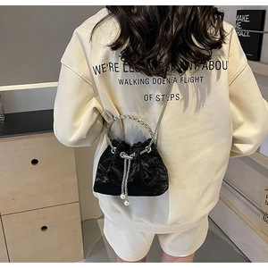 Detail of black velvet drawstring bucket bag with metal handle and pearl accents