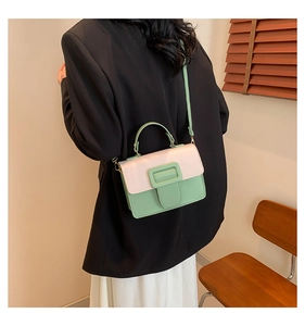 Detail view of crossbody square bag featuring pink flap and sage green body on model