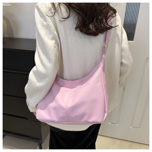 Detail of pink PU leather hobo bag with vertical stitching and adjustable strap on model