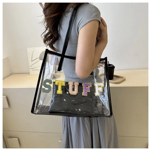 Detail of transparent PVC tote bag with colorful Chenille STUFF letters and black leather trim