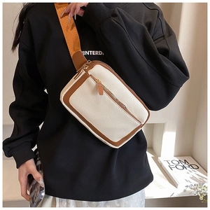 Detail of a two-tone PU leather crossbody bag with wide orange strap on a model